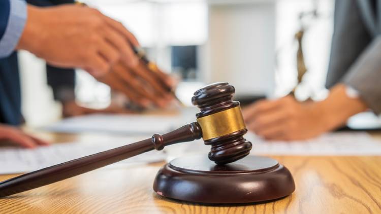A team meeting of business people and a lawyer in formal suits is taking place at a desk