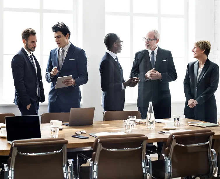 five people in business suits, speaking around a conference table