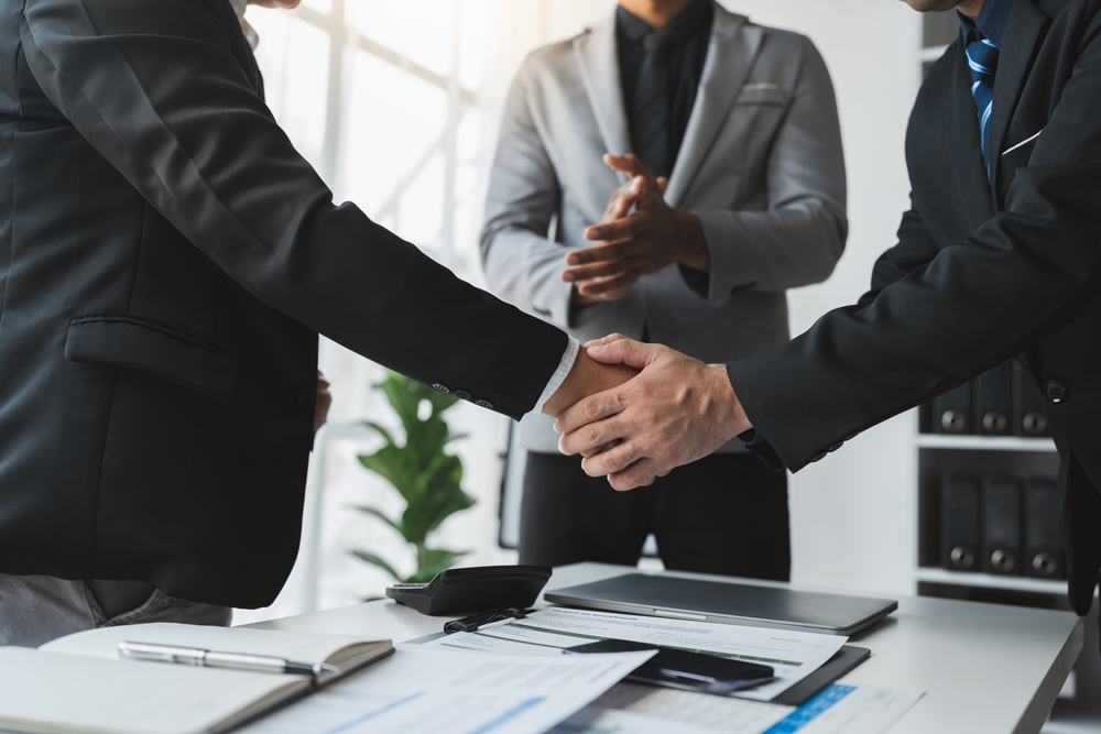 A team of businessmen, investors stand to congratulate their teammates for their successful financial performance