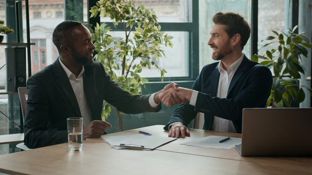 Two happy diverse business men team contract signing shaking hands teamwork cooperation handshaking multiracial businessmen